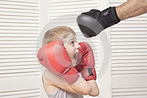 Boy in boxing gloves fights with a man`s hand in a glove.