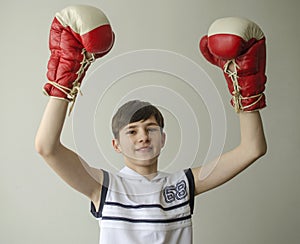 Boy in boxing gloves with raised hands in victory gesture