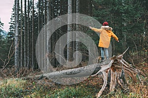 Boy in bright yellow parka puffer jacket walks in pine forest