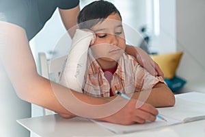 Boy with broken arm in gypsum having help from older brother for homework