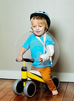 Boy with broken hand in plaster on little bicycle