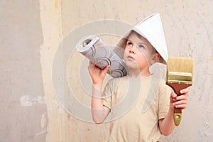 Boy with brush and roll of wallpaper in papper hat