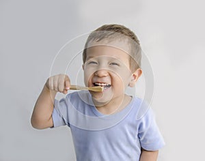 The boy brushes his teeth with a toothbrush.