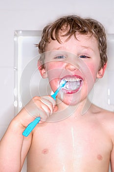 Boy brushing teeth and laughing, messy toothpaste.