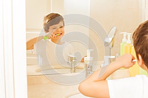 Boy brushing teeth and looking at mirror in bath