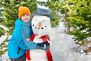 Boy build snowman with red scarf during winter day