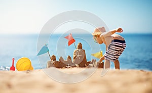 Boy building a sandcastle at the beach in summer