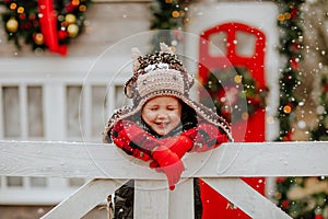 Boy in bull hat and red gloves posing up white fence and making funny faces