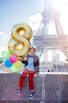 Boy with bunch of colorful balloons in Paris near the Eiffel tower.