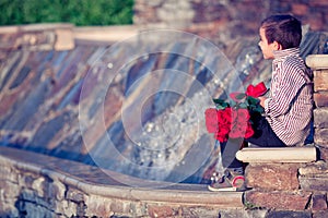 Boy with bunch of red roses waiting