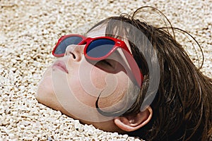 Boy buried in the pebbles on the beach