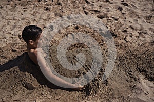 Boy buried in the sand beach