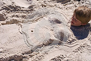 Boy Buried in Sand with Mermaid Body