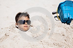 Boy Buried In The Sand On A Sunny Day