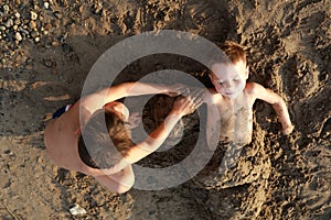Boy buries his brother in sand