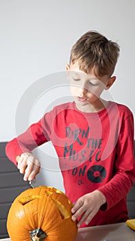 Boy busy carving a pumpkin jack-o-lantern for Halloween - removing the seeds