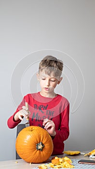 Boy busy carving a pumpkin jack-o-lantern for Halloween - removing the seeds