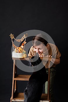 a boy with a cake, he has a birthday, a boy wearing a beige t-shirt and green pants on a black background