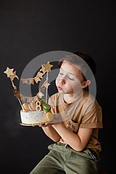 a boy with a cake, he has a birthday, a boy wearing a beige t-shirt and green pants