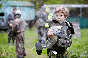 Boy in camouflage holds a paintball gun barrel up photo