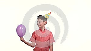 Boy in cap lets air balloon white background. slow