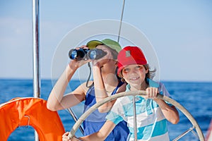 Boy captain with his sister on board of sailing yacht on summer cruise. Travel adventure, yachting with child on family
