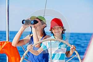 Boy captain with his sister on board of sailing yacht on summer cruise. Travel adventure, yachting with child on family