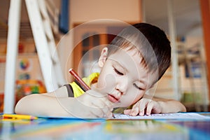 The boy carefully and intently draws in a special photo