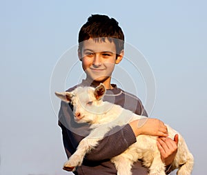 A boy carry a baby goat