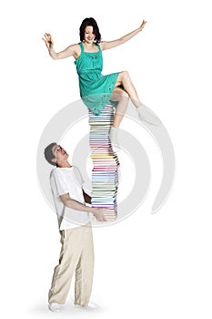 Boy carrying girl on book stack.