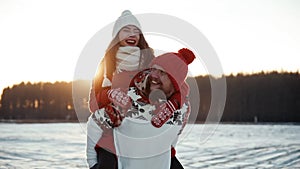Boy carrying his girfriend on his back. Happy young couple dating in winter outside at Xmas, holidays concept. Family