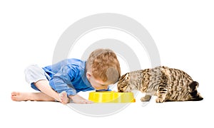 Boy and cat eating from the same bowl