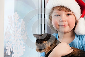 Boy with a cat near the winter window in the house Christmas Eve