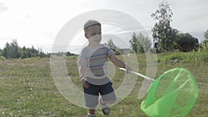 The boy is catching butterflies with a butterfly net.