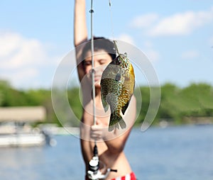 Boy catching a fish in Michigan lake during summer, fishing activity with family. Fun child.