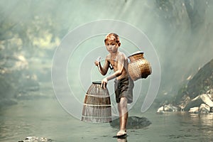 A boy is catching fish in a stream near his home. In the rural areas of Thailand