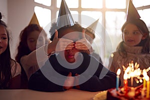 Boy Celebrating Birthday With Group Of Friends At Home Being Given Cake Decorated With Sparkler