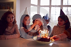 Boy Celebrating Birthday With Group Of Friends At Home Being Given Cake Decorated With Sparkler