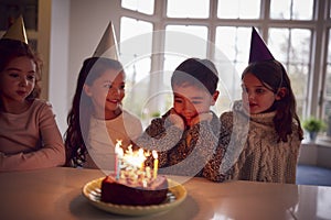 Boy Celebrating Birthday With Group Of Friends At Home Being Given Cake Decorated With Sparkler