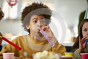 Boy Celebrating Birthday With Party Blower At Party With Friends At Home