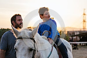 Boy with cerebral palsy and therapist in equine therapy session