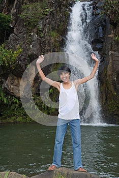 Boy cheering at waterfall