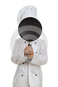 Boy chef hiding his face behind the black frying pan