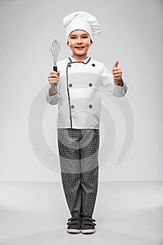 boy in chef& x27;s toque with whisk showing thumbs up