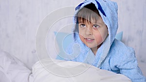 Boy a child in a blue Bathrobe rages at home