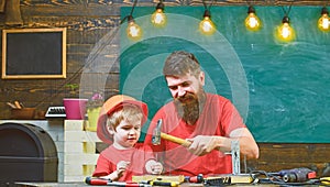 Boy, child busy in protective helmet makes by hand, repairing, work with tools with dad. Father with beard teaching