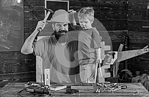 Boy, child cheerful holds toy saw, having fun while handcrafting with dad. Fatherhood concept. Father, parent with beard