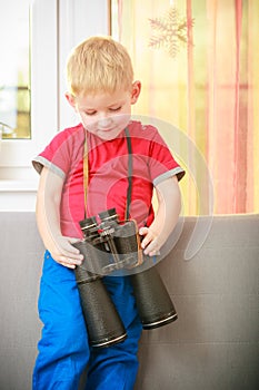 Boy child kid playing with binoculars. At home.