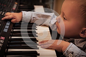 Boy child kid playing on digital keyboard piano synthesizer