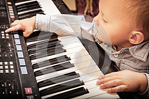 Boy child kid playing on digital keyboard piano synthesizer